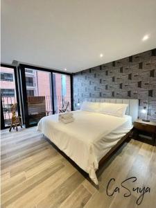 a bedroom with a large white bed with a brick wall at CaSuya Airali apartments with heated pool, gym in city center in Guatemala
