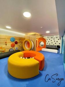 - une chambre pour enfants avec une ottomane jaune et orange dans l'établissement CaSuya Airali apartments with heated pool, gym in city center, à Guatemala