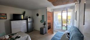 a living room with a couch and a kitchen with a refrigerator at Palm Appart in Biscarrosse-Plage