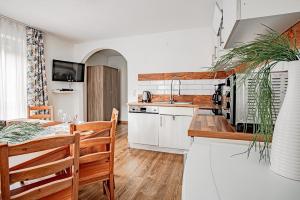 eine Küche mit weißen Schränken und einem Tisch mit einem Esszimmer in der Unterkunft Apartments Leszek Elis 141 in See