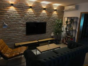 uma sala de estar com uma parede de tijolos e uma televisão de ecrã plano em Holiday home Casa Rio em Vinkovci