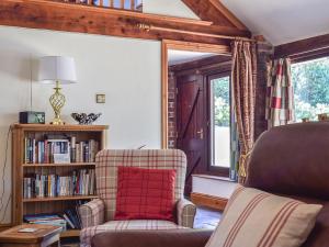 ein Wohnzimmer mit einem Stuhl und einem Bücherregal in der Unterkunft Angel Cottage in Oswaldkirk