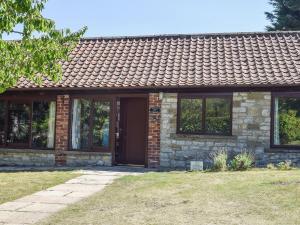 Casa de piedra con puerta y ventanas marrones en Angel Cottage, en Oswaldkirk