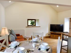 a living room with a table and a television at Lake View Farm in Watermillock