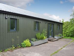 a green building with plants on the side of it at Juniper Barn in Westward