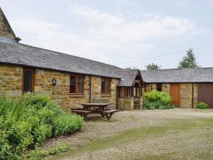 a stone cottage with a picnic table in front of it at Swallow Barn in Banbury