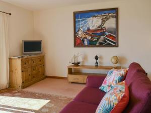 a living room with a couch and a tv at Seashore Retreat in Johnshaven