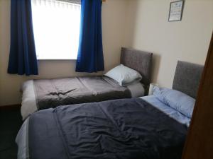 a bedroom with two beds and a window with blue curtains at Impeccable 2-Bed Flat in Wick in Wick