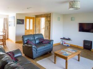 a living room with a leather couch and a table at Grieves Cottage in Portmahomack