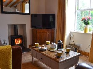a living room with a coffee table and a fireplace at Bwthyn Pabi in Penmachno