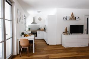 a white kitchen with a table and a television at Apartmán s nádherným výhledem v centru Harrachova in Harrachov