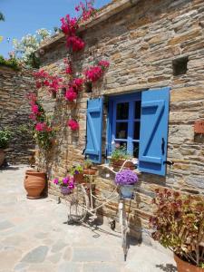 a stone house with blue shutters and flowers on it at Saint Louis in Andros
