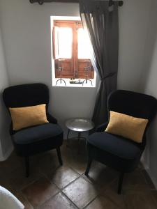 two chairs and a table in a room with a window at Casa Aire de Lecrin in Pinos del Valle