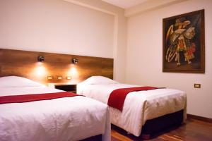 a hotel room with two beds and a painting on the wall at Zans Apartments Cusco in Cusco