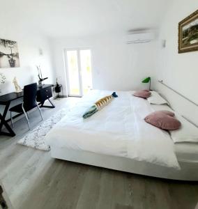 a large white bed in a room with a desk at Alojamento local "CASA BRANCA" in Albufeira
