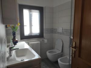 bagno con lavandino, servizi igienici e finestra di A due passi dal Gran Sasso a Fano a Corno