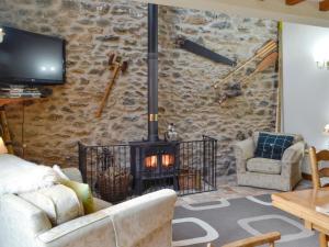 a living room with a stone wall with a fireplace at The Hen House in Llanfair-ar-y-bryn