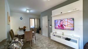 a living room with a television on a wall at Cobertura de 3 quartos com churrasqueira e piscina in Guarujá