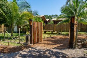 um portão de madeira em frente a uma cerca com palmeiras em Cabana Fluir - Taipu de Fora - Península de Maraú em Barra Grande