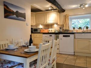 a kitchen with a wooden table with chairs and a sink at Taylors Cottage in Threlkeld