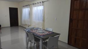 ein Esszimmer mit einem Tisch, Stühlen und einer Tür in der Unterkunft Casa de Temporada Aconchego in Macaé