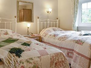 Duas camas individuais num quarto com um espelho. em Manor House Cottage em Pickhill