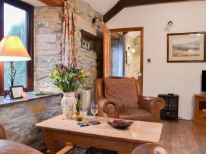 a living room with a chair and a table at Campion Cottage in Saint Teath