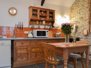 a kitchen with a wooden table and a microwave at Campion Cottage in Saint Teath