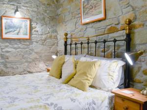 a bedroom with a bed and a stone wall at Campion Cottage in Saint Teath