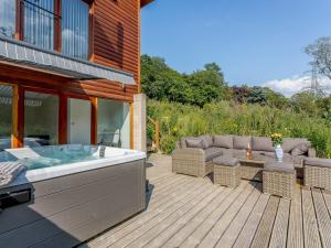 bañera de hidromasaje en una terraza de madera con sofá en Waterside Lodge Thirteen - Uk11853, en Southowram