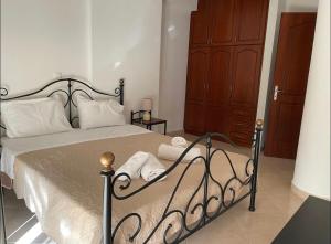 Cette chambre comprend un lit avec des draps blancs et une armoire en bois. dans l'établissement Nice Cosy apartment in Igoumenitsa, à Igoumenítsa