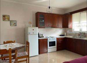cocina con armarios de madera y nevera blanca en Nice Cosy apartment in Igoumenitsa en Igoumenitsa