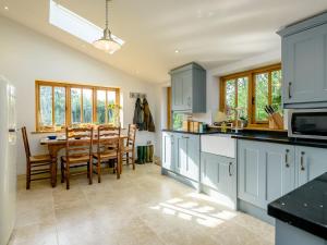 a kitchen with blue cabinets and a dining room at Barn End Cottage in Kelsale