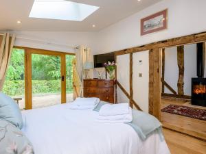 Barn End Cottage في Kelsale: غرفة نوم بسرير ابيض وموقد