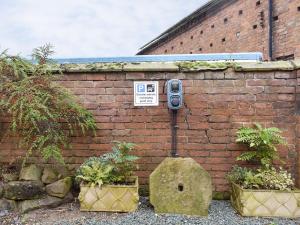 un muro di mattoni con un altoparlante accanto a due piante di Skylark - Uk30746 a Acton Trussell