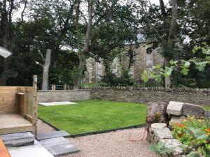 a garden with a stone wall and a lawn at Harland Cottage in Castletown