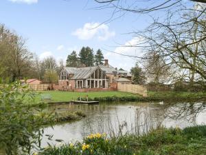 a large house with a pond in front of it at Lily Pad Lodge in Donington on Bain