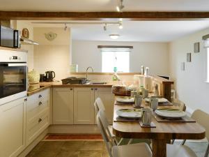 een keuken met een houten tafel met stoelen erin bij Beech Cottage in Rhewl