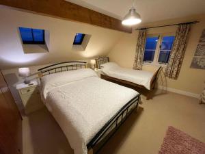 een slaapkamer met 2 bedden en 2 ramen bij Beech Cottage in Rhewl