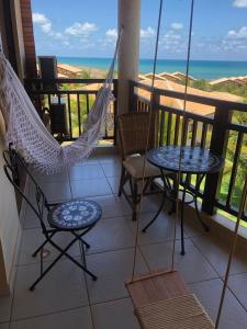 a porch with two chairs and a hammock and the ocean at Condomínio Encantador Piscina e Praia E12 in Zumbi