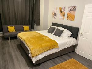 a bedroom with a large bed with a yellow blanket at Modern 4 Bedroom House 10 mins from East Croydon with Garden and Free parking in South Norwood