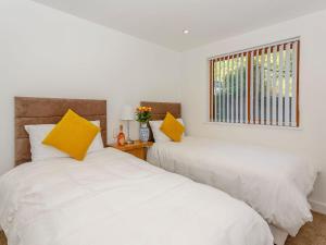 two beds in a white room with yellow pillows at Waterside Lodge Sixteen - Uk13038 in Southowram