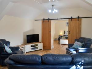 a living room with a leather couch and a television at Penrhos Bach in Llanerchymedd