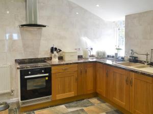 a kitchen with wooden cabinets and a stove top oven at Penrhos Bach in Llanerchymedd