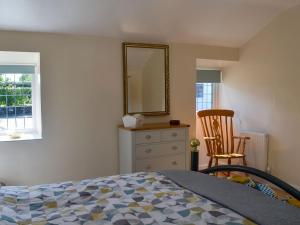 a bedroom with a bed and a mirror and a chair at Penrhos Bach in Llanerchymedd