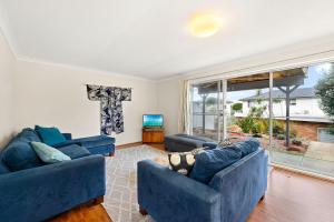 a living room with two blue couches and a large window at Summerside 43 Lentara Street in Fingal Bay