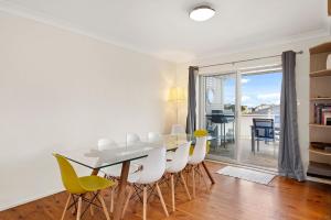 a dining room with a table and chairs and a balcony at Summerside 43 Lentara Street in Fingal Bay