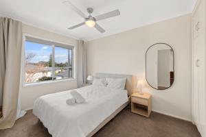 a bedroom with a bed with a mirror and a window at Summerside 43 Lentara Street in Fingal Bay