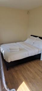 1 dormitorio con 1 cama con sábanas blancas y suelo de madera en Dartford Cosy and Spacious 3 bedroom house Netflix and Sport Channels, en Dartford
