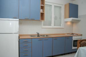 cocina con armarios azules y nevera blanca en Apartments and rooms by the sea Zuljana, Peljesac - 3164 en Žuljana